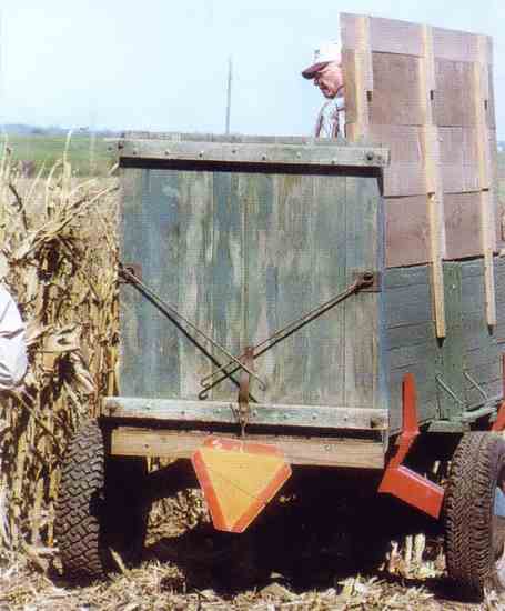 This vintage corn wagon has a "scoop board" that drops down on the rear end for the farmer to stand on while unloading. The iron rods serve as ground supports.